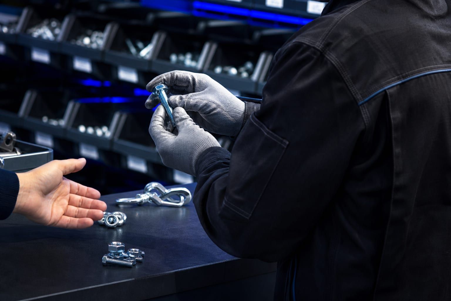 Magasinier présentant une pièce de visserie à un client au comptoir